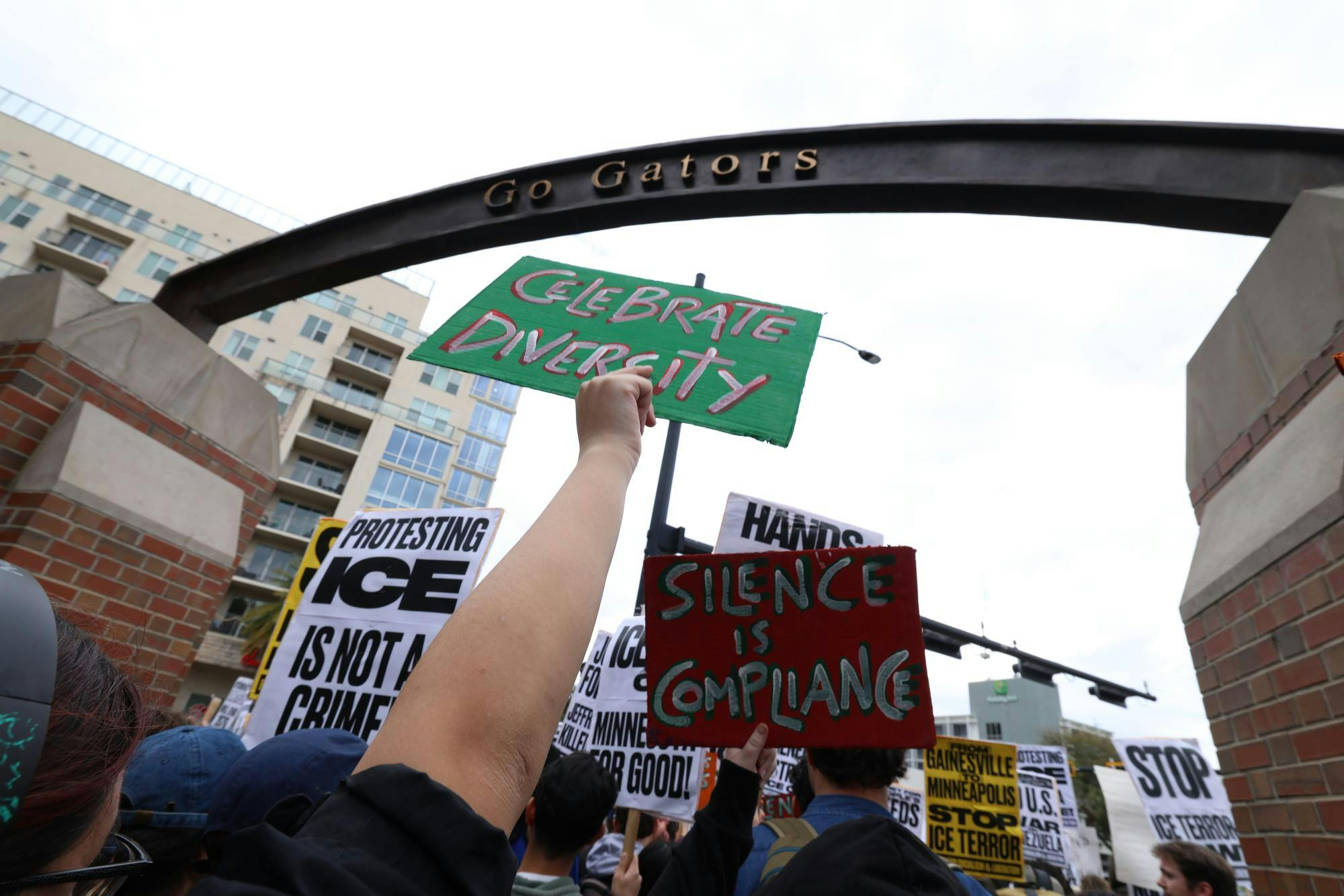 A protestor holds a sign under the Go Gators sign on UF campus during a protest organized by the Party for Socialism and Liberation, Friday, Jan. 30, 2026 .