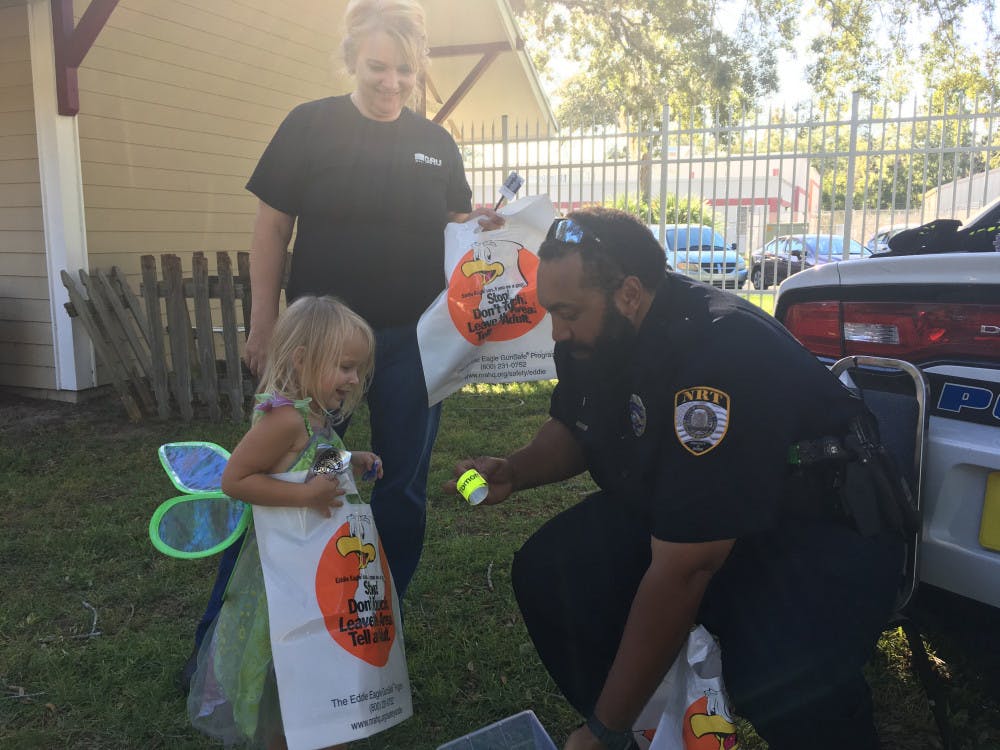 Three-year-old Chloe Momanis, dressed as Tinker Bell, giggles as Gainesville Police Officer Ernest Graham readies a trick-or-treat package of candy, a slap bracelet and a free baggie to give her on Thursday evening at Gainesville Fire Rescue’s 11th annual Screaming for Safety event near its headquarters, located at 1025 NE 13th St.