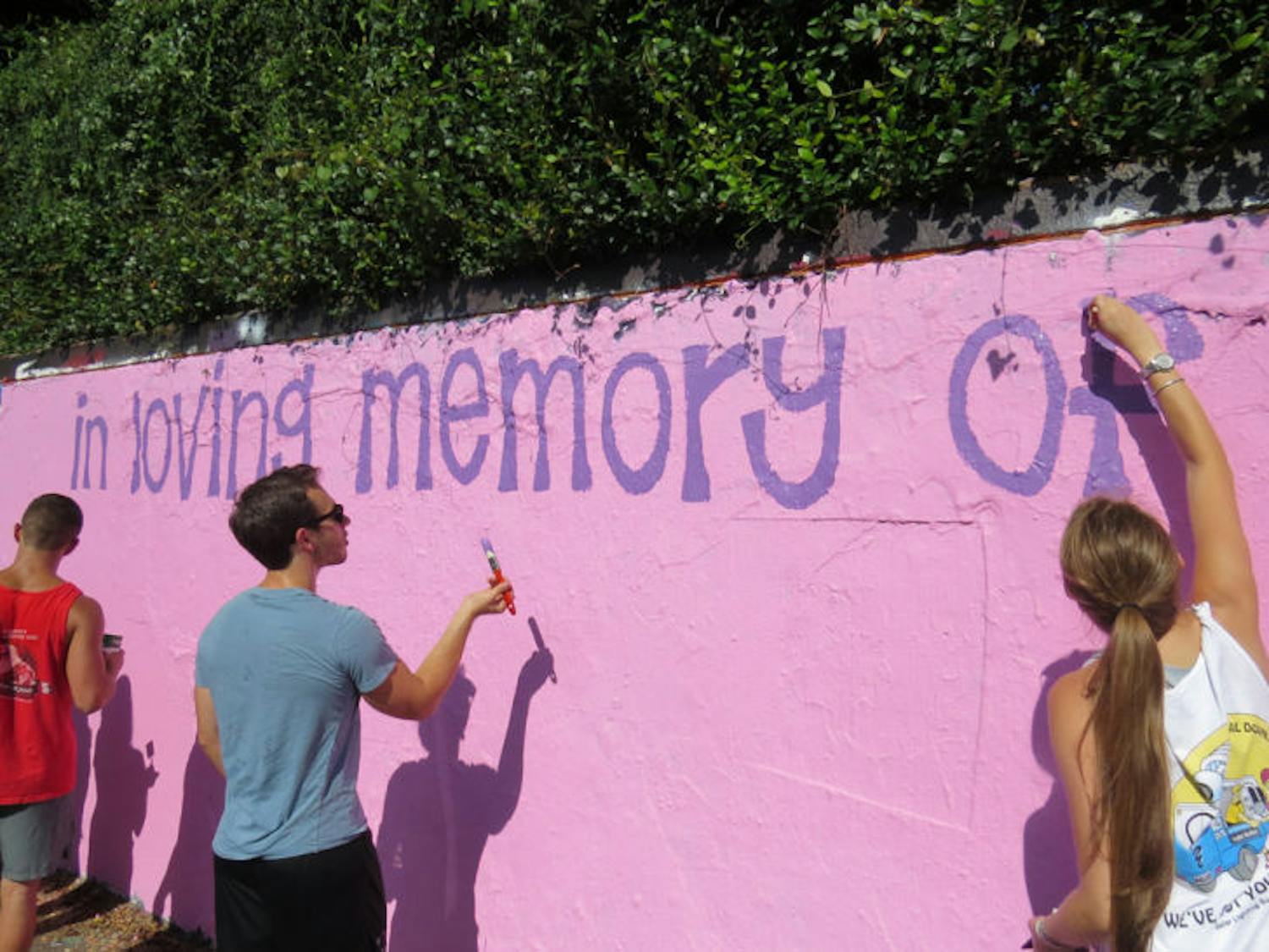 Recreation, parks and tourism junior Paige Gross, right, and biology senior Matt Seskin, center, paint the 34th Street Wall with friends Sunday in memory of Lauren Marcus, a recent UF graduate who died Aug. 19.