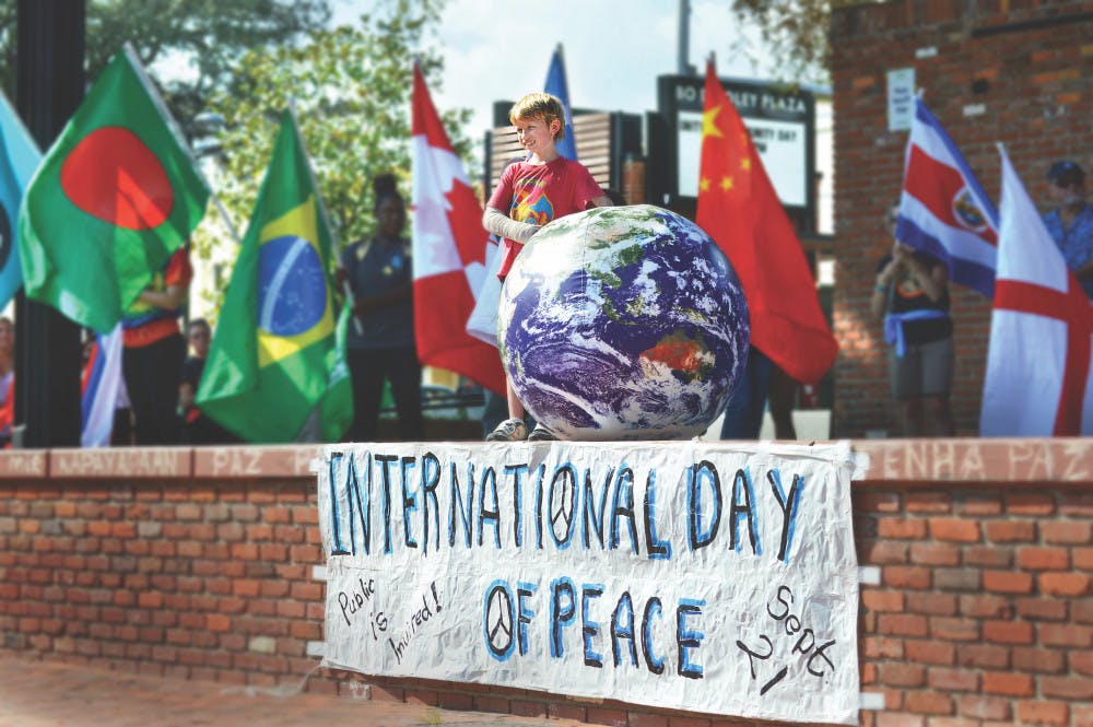 Eight-year-old Andrew Bittikoffer stands next to a model of the Earth during a flag ceremony promoting global unity as a part of the celebration of the International Day of Peace held on Bo Diddley Community Plaza.