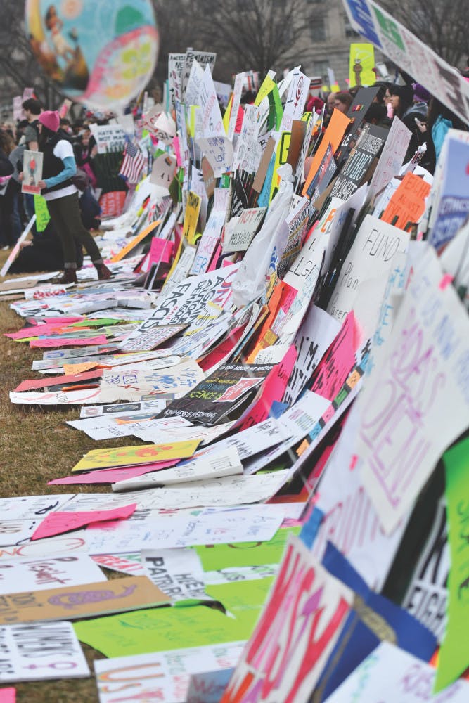 Signs line a small fence in front of the White House while many protesters chant, “Welcome to your first day, we will never go away.” Thousands of people placed their signs on the temporary Ellipse fence to create a “wall” outside the White House in 2017.