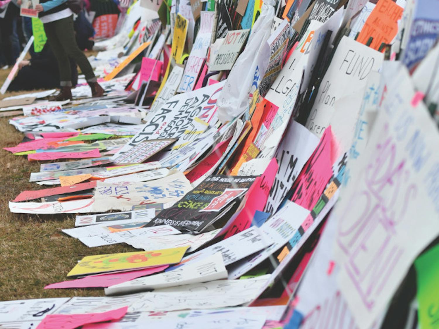 Signs line a small fence in front of the White House while many protesters chant, “Welcome to your first day, we will never go away.” Thousands of people placed their signs on the temporary Ellipse fence to create a “wall” outside the White House in 2017.