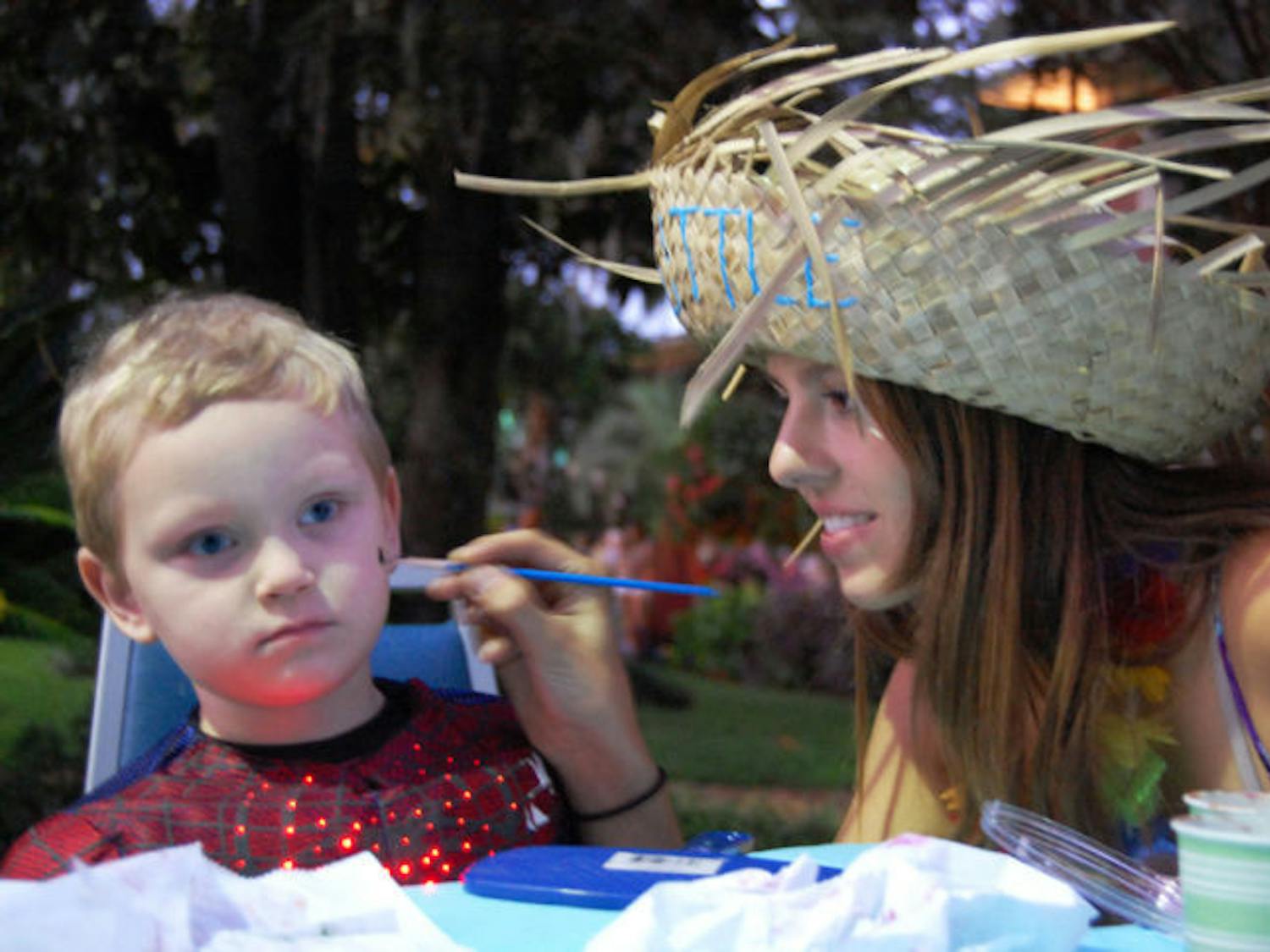 UF nursing freshman Brittany Reeser, 18, paints a spider on 3-year-old Jacob Rowland’s cheek Thursday in front of the Alpha Delta Pi house. The face-painting was a part of Ghouls, Goblins and Greeks held on Sorority Row for children.