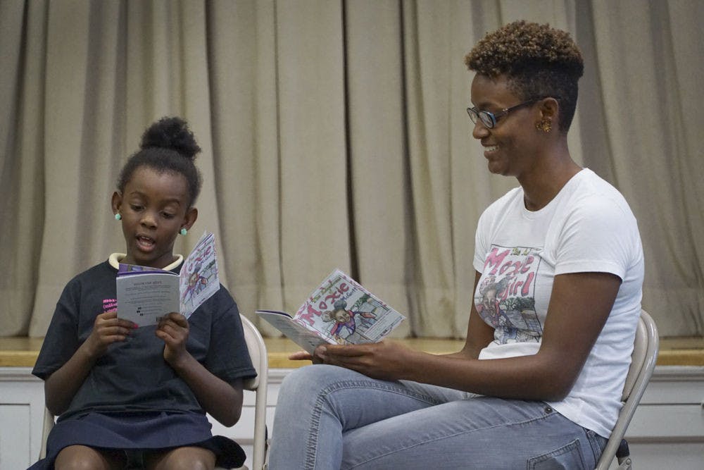 <p>Eight-year-old Natalie McGriff, author of "The Adventures of Moxie McGriff," reads the comic book to an audience of about 20 people with her mother, Angie Nixon, on Sept. 28, 2015, at First Presbyterian Church. Nixon encouraged her daughter to write a superhero story about herself to raise her self-esteem and teach her a love of reading.</p>