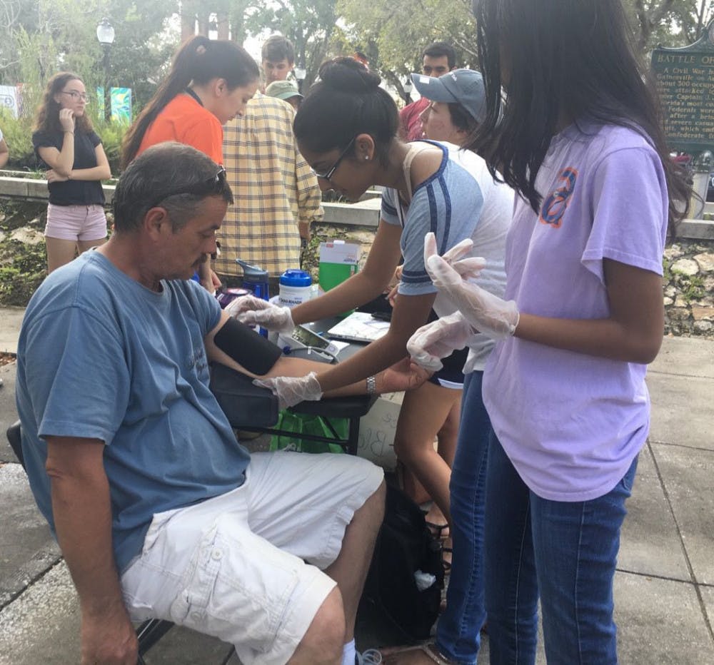Rianna Haniff, a 20-year-old UF biochemistry and molecular biology junior, conducts her first blood pressure screening on Steve Mclain, a Gainesville resident. The screenings have taken place every Sunday since September and are a part of the new UF chapter of the organization Hearts for the Homeless.