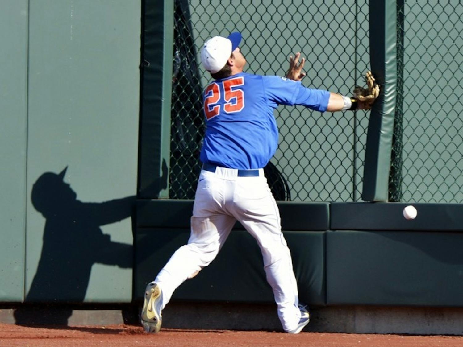 Florida right fielder Preston Tucker collides with the fence as he chases a ball hit for a triple by Kent State's David Lyon in the sixth inning of an NCAA College World Series elimination baseball game in Omaha, Neb., Monday, June 18, 2012.