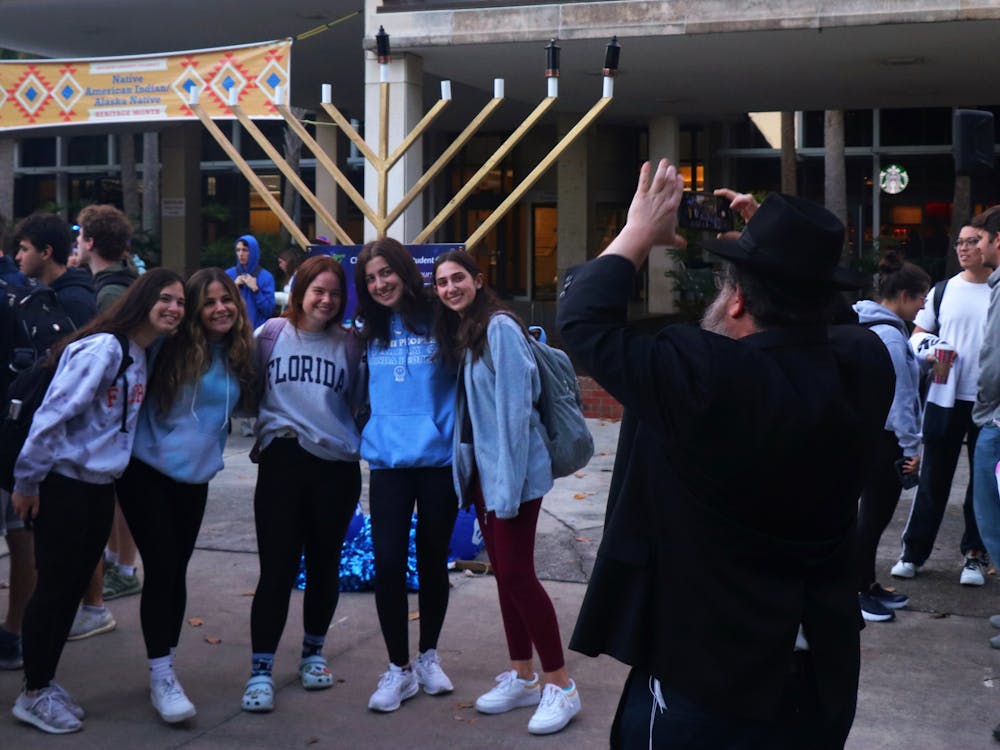 Rabbi Berl Goldman takes a picture of a group of girls in front of the menorah at the Plaza of Americas on Monday, Nov. 29, 2021.