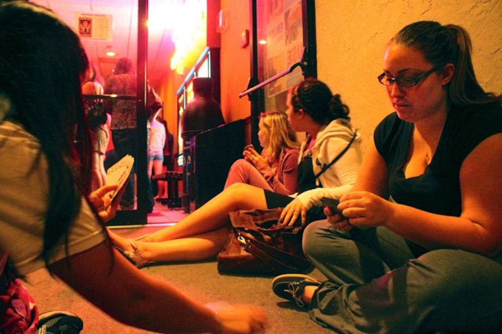 <p>UF alumna Anh-Thu Nguyen, 23, plays cards with animal biology senior Chelsea Rence, 24, while waiting in line for the 3:10 a.m. showing of “The Hunger Games.”</p>