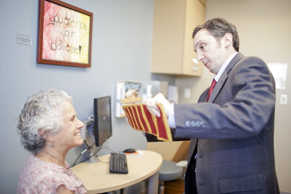 <p>Dr. Michael Okun (right), a doctor at the UF Center for Movement Disorders and Neurorestoration, interacts with a patient. Okun was a member of a Champions for Change panel at the White House last Monday addressing Parkinson’s treatments and research.</p>