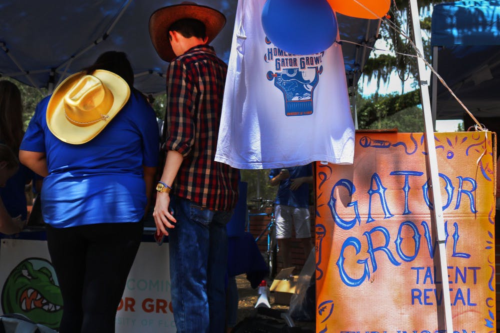 Two students speak with members of the UF Homecoming &amp; Gator Growl team Tuesday afternoon at Turlington Plaza during the Gator Growl Talent Announcement. More than 100 people attended the announcement to hear that country music singer Chase Rice will be performing on October 4. The event also featured a photo station and merchandise giveaways.