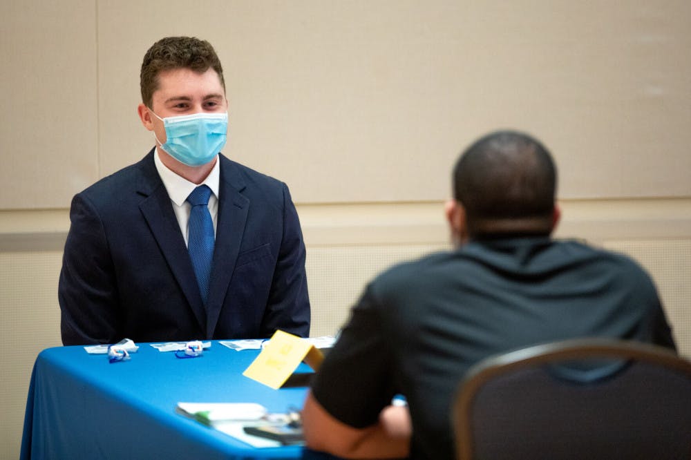 Photo of a student speaking to a recruiter while wearing a face mask