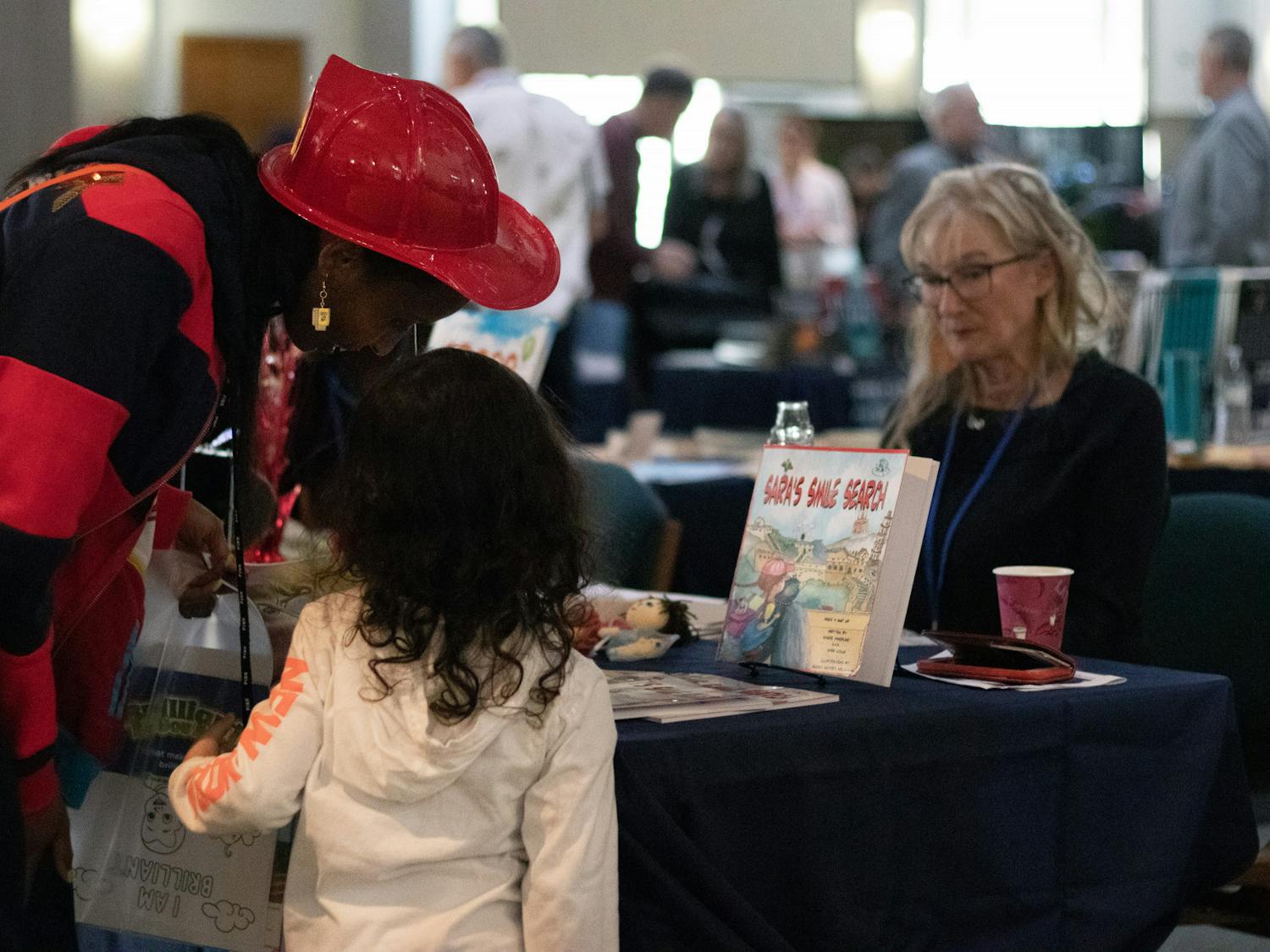 Festival-goers stop by Jill Clark’s booth to read from the children&#x27;s poetry books she wrote Saturday, Jan. 28, 2023.