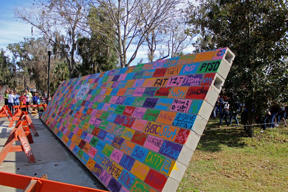 The wall is falling after being pulled down by dozens of volunteers at UF’s Inter-Residence Hall Association Social Justice's Writing on the Wall Program on Friday. The wall, which had been painted over with insults people had been told, was torn down and demolished as a means of catharsis.