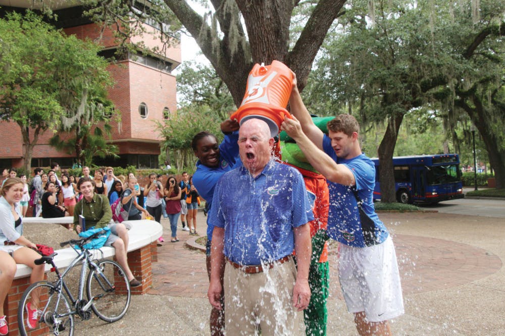 Gator volleyball blocker Simone Antwi and Gator quarterback Jeff Driskel dump ice water on UF President Bernie Machen on Turlington Plaza on Monday. The ALS Ice Bucket Challenge raises awareness of the disease and collects donations.