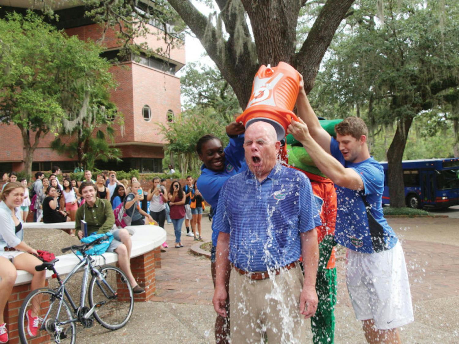 Gator volleyball blocker Simone Antwi and Gator quarterback Jeff Driskel dump ice water on UF President Bernie Machen on Turlington Plaza on Monday. The ALS Ice Bucket Challenge raises awareness of the disease and collects donations.