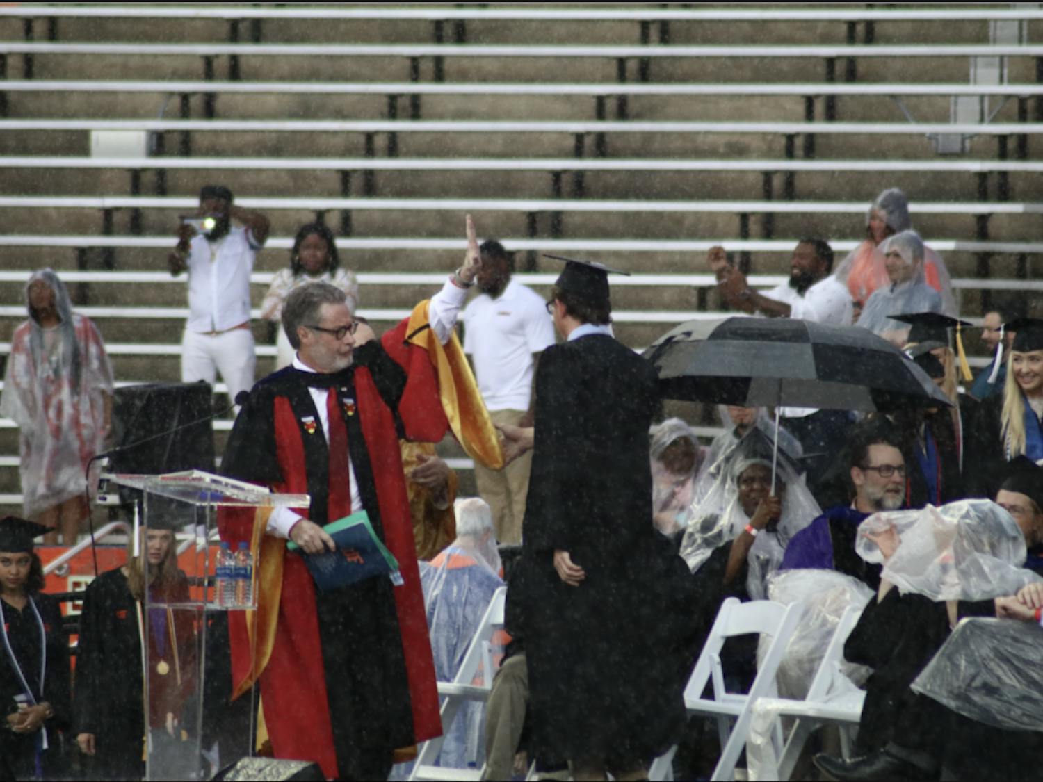 College of Liberal Arts and Sciences Dean, David Richardson, gestures to pause the commencement ceremony. Richardson announced the ceremony would be delayed by 30 minutes, but the ceremony was later moved to an inside
hallway of the stadium.