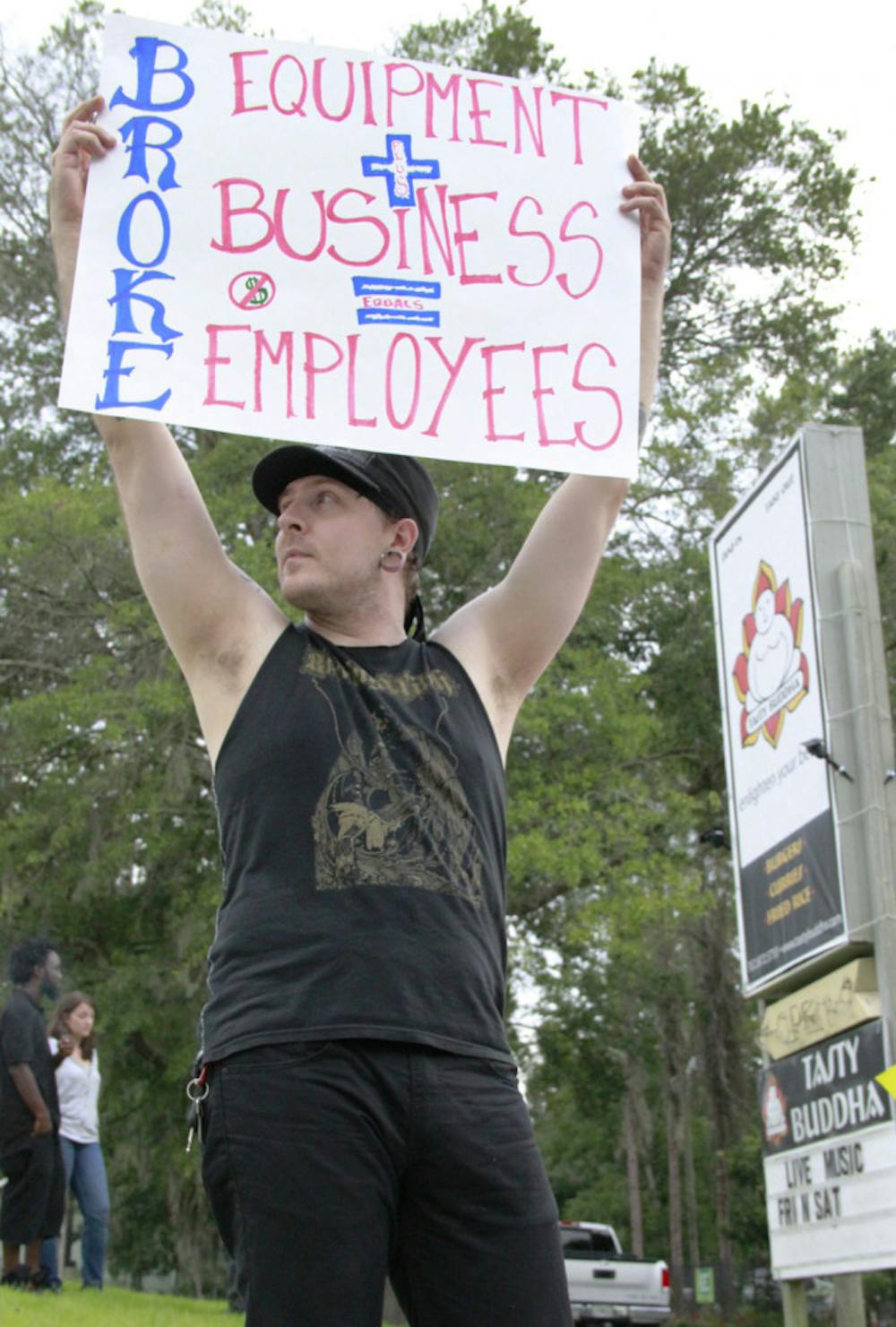 <p>Striking Tasty Buddha cook Dustin Horn protests outside the restaurant Saturday. Employees say there has been a history of bounced checks.</p><div> </div>