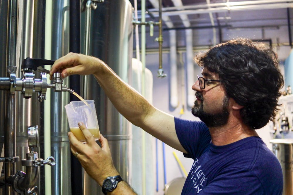 Head Brewer John Denny draws a sample of fermenting beer in order to test its density. Testing for density, also known as specific gravity, is used to determine how much sugar the yeast has consumed.