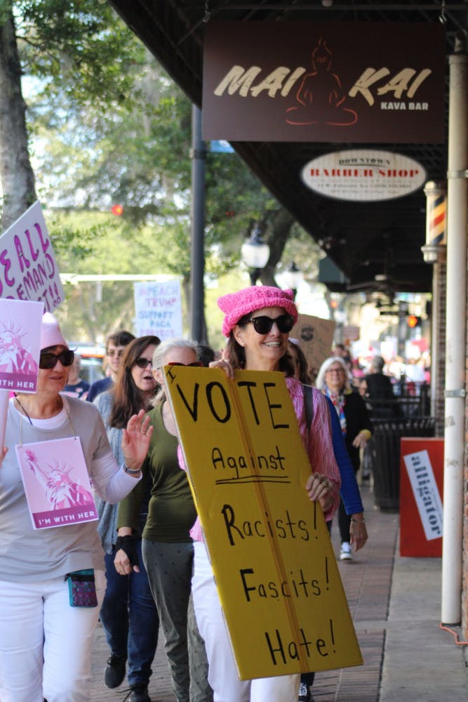 Protesters march past businesses on West University Avenue on Sunday afternoon to raise support for more female involvement in American politics. Donations were also collected for areas affected by the 2017 hurricane season.