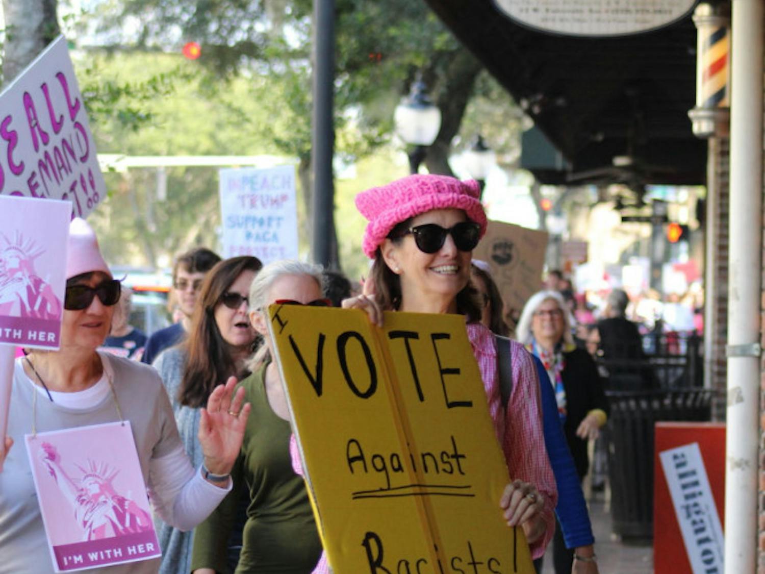 Protesters march past businesses on West University Avenue on Sunday afternoon to raise support for more female involvement in American politics. Donations were also collected for areas affected by the 2017 hurricane season.