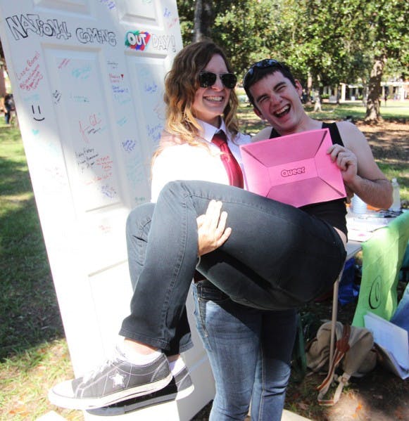Olivia DeMonte, a 20-year-old psychology and women’s studies junior, lifts up Iain Randall, a 19-year-old engineering sophomore, during National Coming Out Day.