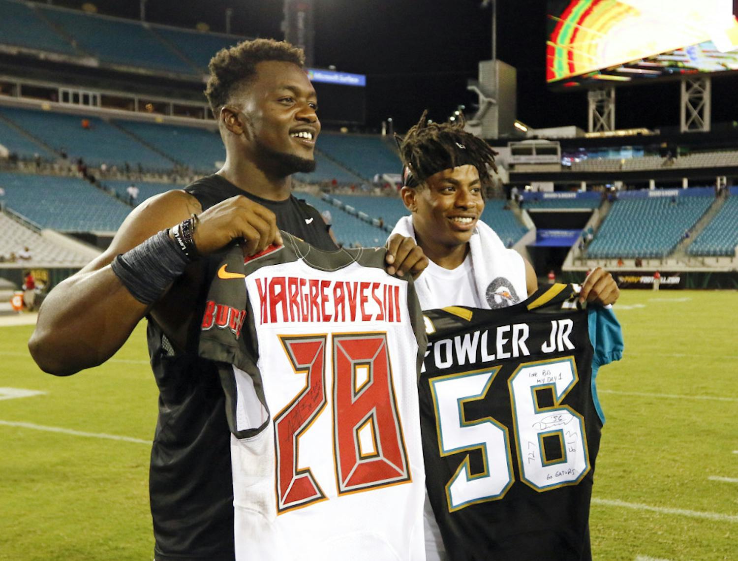 Former University of Florida teammates, Jacksonville Jaguars' Dante Fowler, left, and Tampa Bay Buccaneers' Vernon Hargreaves, right, pose for a photo after they signed and exchanged jerseys after an NFL preseason football game in Jacksonville, Fla., Saturday, Aug. 20, 2016. (AP Photo/Stephen B. Morton)