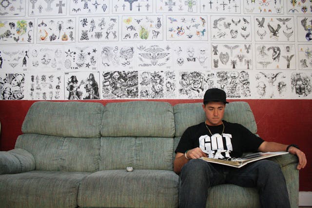 Addiction Tattoo customer Mike Beall, 22, looks through a portfolio of tattoos on Thursday evening. Addiction Tattoo is holding a Halloween Hottest Tattoo and Piercing Contest with a $250 prize pack and a raffle with all proceeds going to St. Francis House and the Ronald McDonald House.