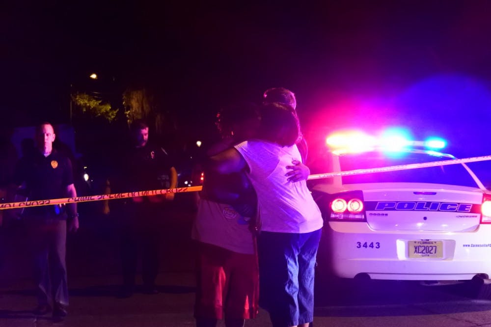 About 100 feet from where the shooting took place, a man emerges from behind yellow caution tape to hug a woman and then hand her a sleeping baby in early morning of July 28.