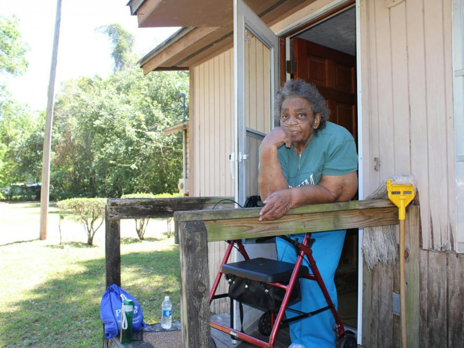 Mamie Leath, 89, watches as UF students help clear fallen leaves from her home in Gainesville’s Porters Community on Saturday as a part of UF Student Government’s inaugural The Big Event. Leath said she felt grateful the students volunteered their time clearing her yard of leaves and miscellaneous junk, like rusted bicycles and an armchair. 