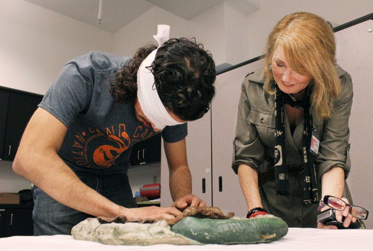 Julian Rey, a 19-year-old biomedical engineering sophomore, attempts to guess the shape of a sculpture while receiving hints from annual volunteer and artist Diane Voyentzie on Saturday during MindSight at the Samuel P. Harn Museum of Art.