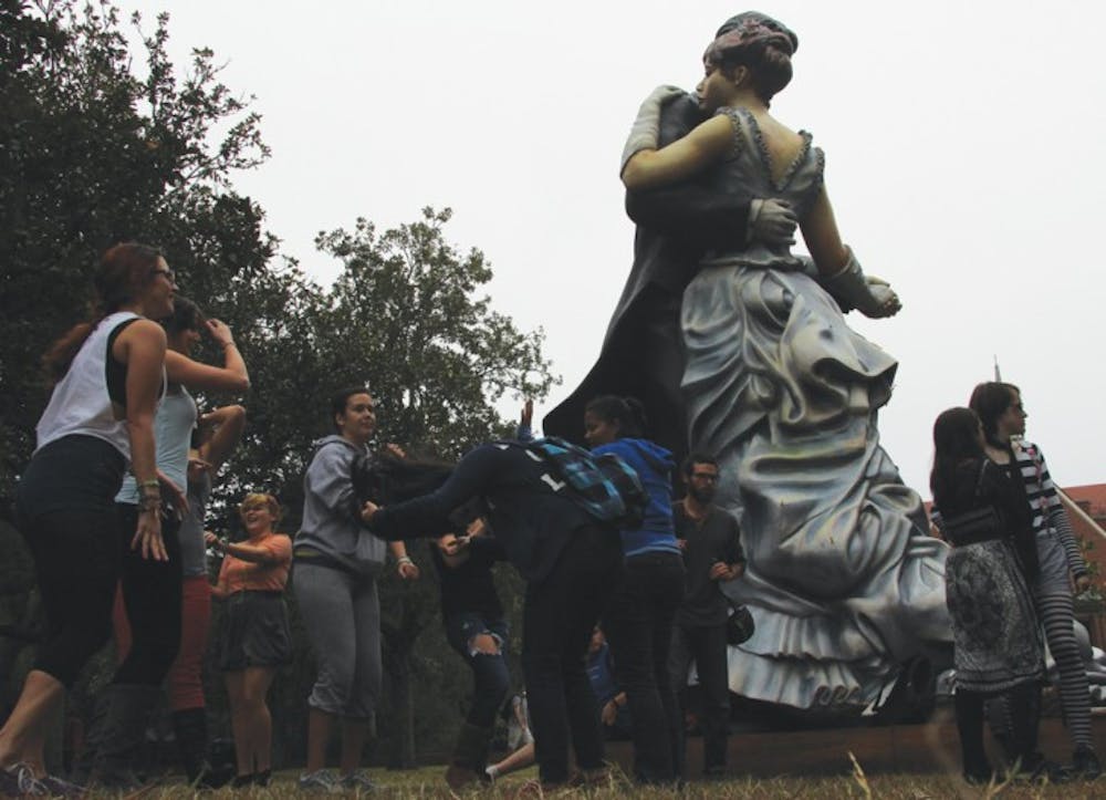 <p>Students dance next to the “Whispering Close” statue on Plaza of the Americas as part of the Queer Sadie Hawkins Dance on Wednesday afternoon. The dance was meant to spur discussion about heteronormativity.</p>
