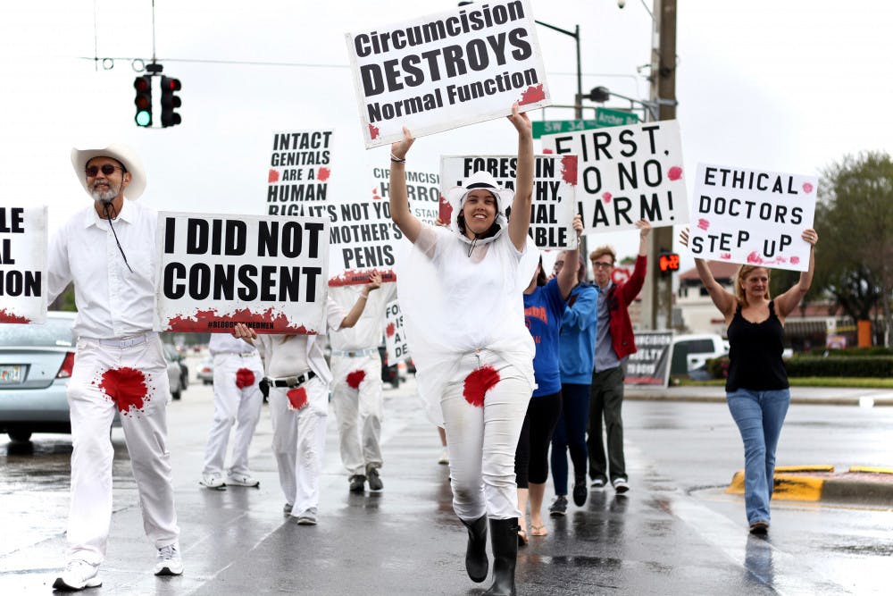 Stacey Van Buskirk, 24, a University of Michigan alumna, leads a group of more than a dozen protesters across Southwest 34th Street on Thursday morning. The protesters were comprised of the nonprofit group Bloodstained Men and Their Friends, who protest "children and future generations from genital cutting," as stated on their flyer.