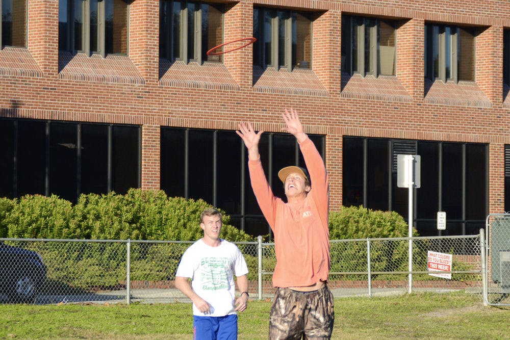 Avery Jordan, a 21-year-old UF finance senior, leaps to catch an Aerobie flying ring in front of 22-year-old Mitch McNall, also a finance senior, on Norman field on Monday afternoon. Jordan said he and his friends often tossed the ring on Norman field after his friends got the ring for Christmas.