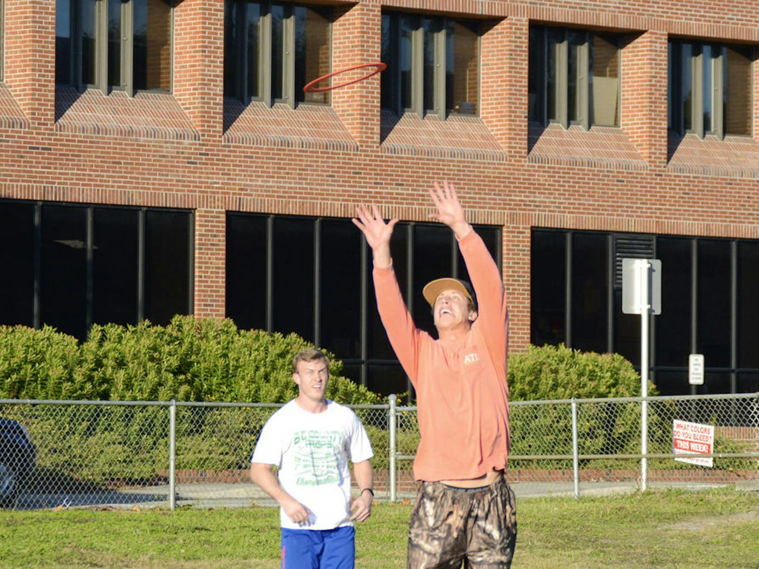 Avery Jordan, a 21-year-old UF finance senior, leaps to catch an Aerobie flying ring in front of 22-year-old Mitch McNall, also a finance senior, on Norman field on Monday afternoon. Jordan said he and his friends often tossed the ring on Norman field after his friends got the ring for Christmas.