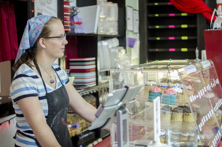 Eleanor McKenna, a 23-year-old “cupcake elf” at Sarkara Sweets downtown, waits to help incoming customers on Monday.
