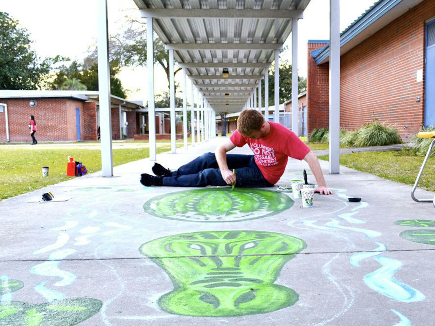 Brandon Peebles, 21, an art coordinator for Project Makeover, paints an alligator on the sidewalk at W.A. Metcalfe Elementary School. Members and volunteers painted murals all around the school, including musical instruments in the music room, a Dr. Seuss themed kindergarten area and an ocean scene in the cafeteria.