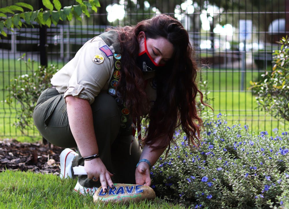 Scout places painting healing stone labeled "brave" at the UF Health Children's Healing Garden