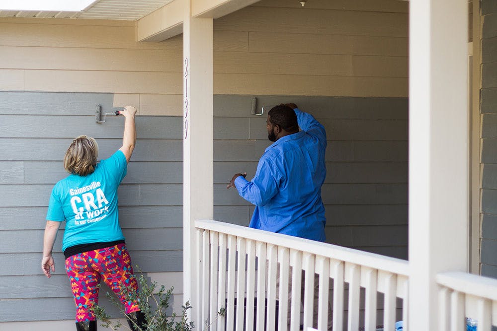 

Two people paint a Gainesville residence gray. The Gainesville Community Redevelopment Agency's residential paint program helps local residents with pressure washing and painting costs.&nbsp;

