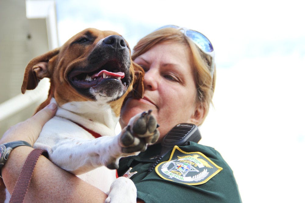 Officer Debra Scott of the Alachua County Jail hugs Maggie, a 10-month-old dog, at the Paws on Parole Unleashed program graduation Monday morning. The program pairs adoptable dogs with inmates who train them for eight weeks to pass the American Kennel Club’s Canine Good Citizen test.