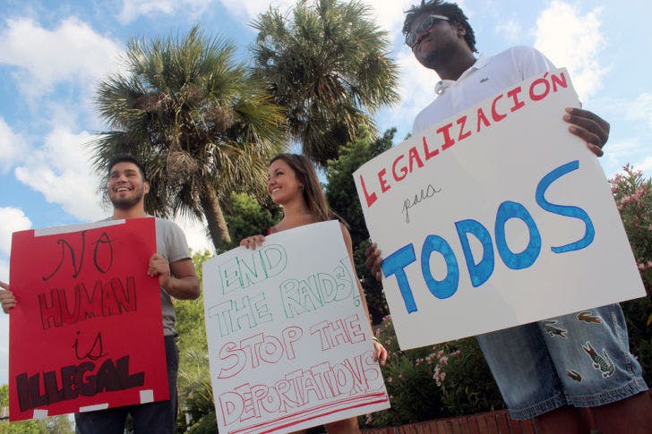 Students for a Democratic Society members hold signs Friday by University Avenue and 13th Street. They demanded Florida driver’s licenses for undocumented people and legalization for all immigrants.