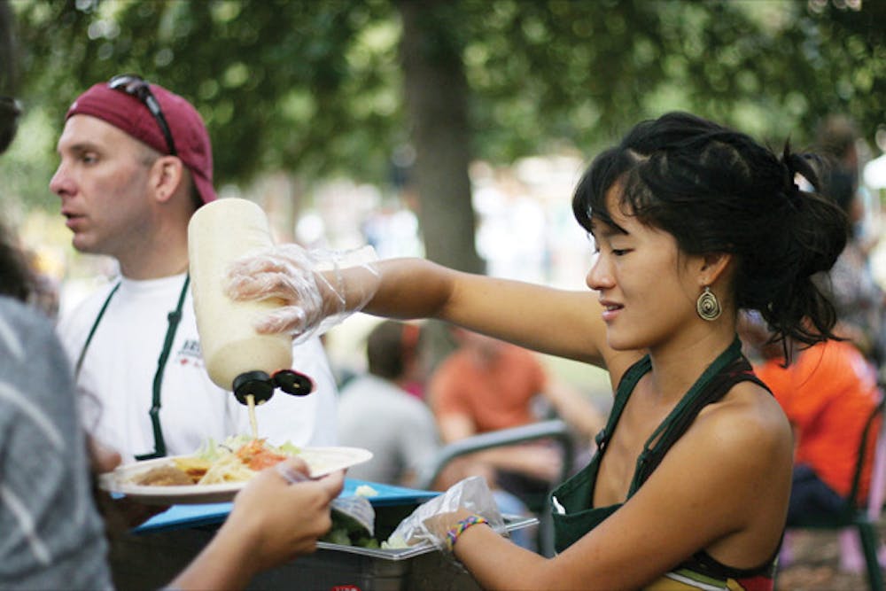 <p>Horticultural science senior Van Tran, 22, serves salad as a volunteer at Krishna Lunch on Plaza of the Americas on Wednesday.</p>