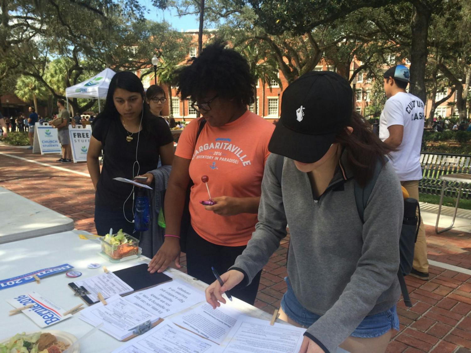 Nuzhat Zaman, Jada Sears and Stephanie Yuan look at information about the Alachua County Revolution.