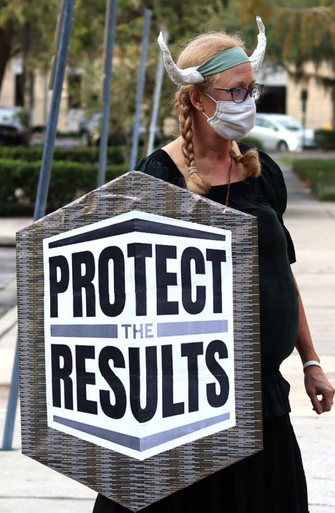 Sarah Younger holds a shield stating “Protect the Results” during the rally held at the Alachua City Hall on Wednesday, Nov. 4, 2020. Younger said, "It ain't over 'til the fat lady sings, and I'm not singing yet." (Lauren Witte/Alligator Staff)