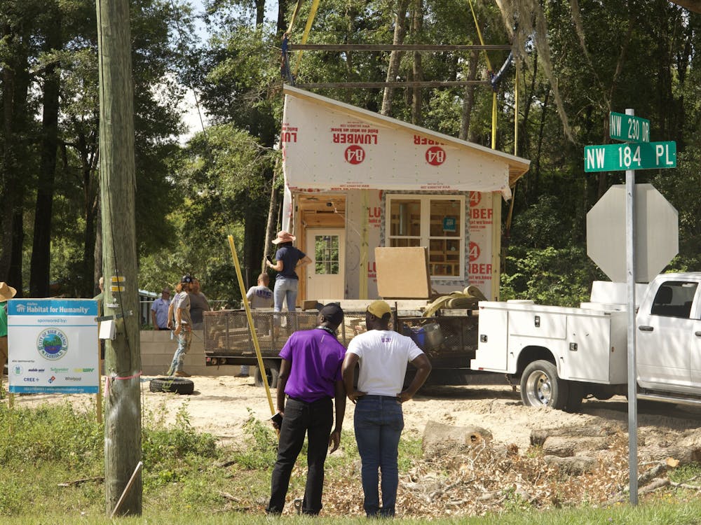 <p>Alachua Habitat for Humanity, Santa Fe professors and construction workers prepare to place the second half of a modular home as two spectators watch at High Springs on Thursday, June 8, 2023.</p>