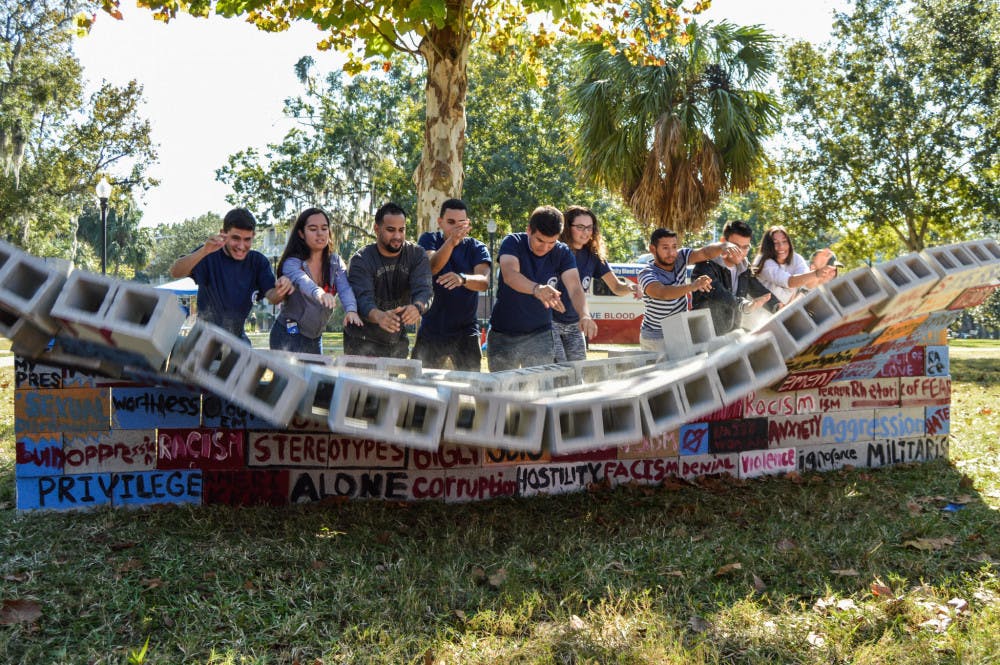 <p dir="ltr">The UF Hispanic Student Association and Hispanic-Latino Affairs break down a wall made of cinder blocks for a unity demonstration behind the Hub on Thursday afternoon. Throughout the day, the organizations invited students to write words and phrases they found harsh and cruel, with the intent to tear them down.</p>