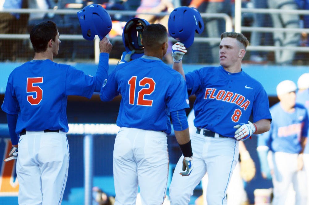 Harrison Bader (8) celebrates with Dalton Guthrie (5) and Richie Martin (12) after hitting a home run during Florida's 22-3 win against Rhode Island on Saturday at McKethan Stadium.