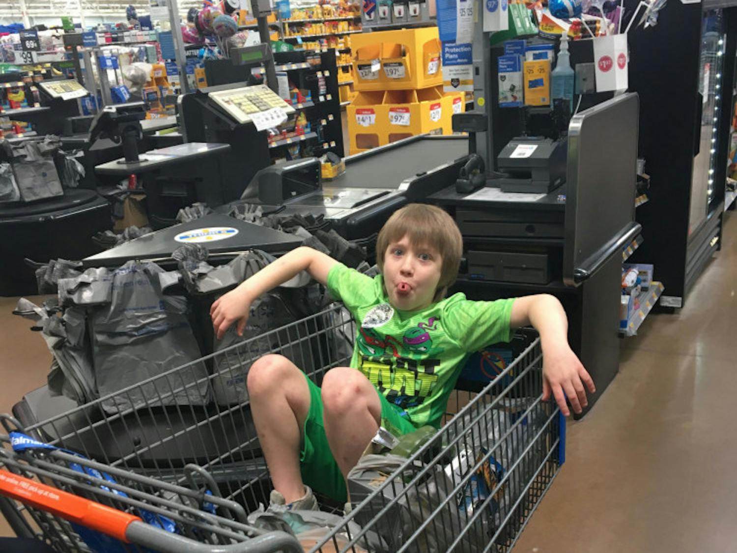 Logan Robbins sitting in his shopping cart of purchased items.
&nbsp;