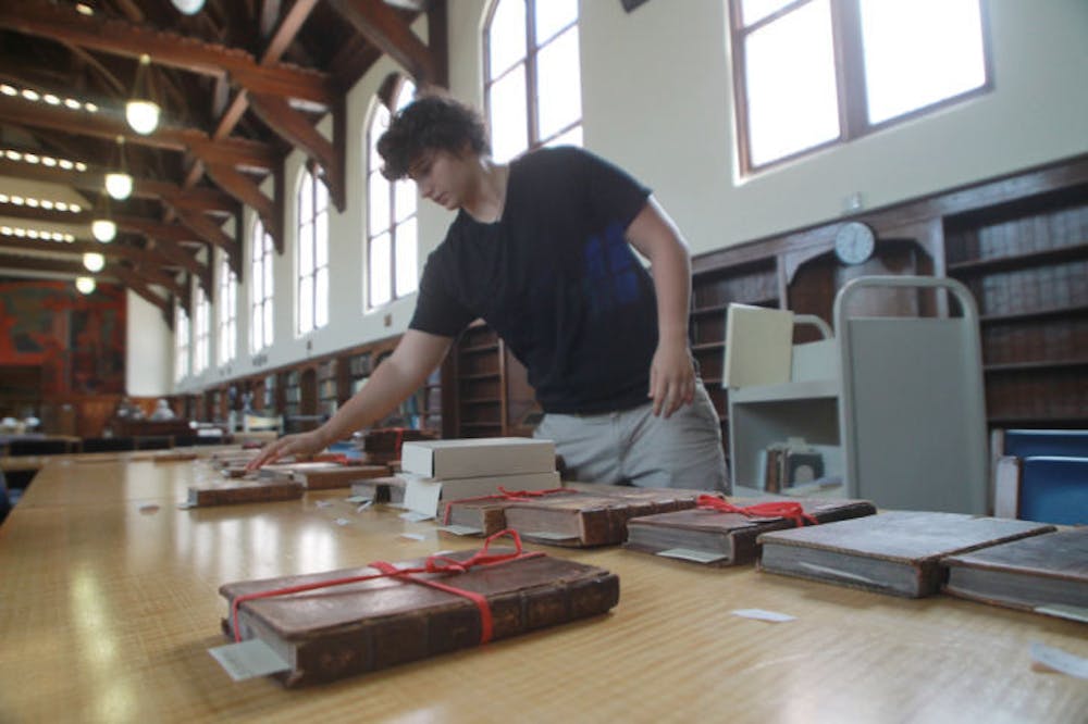 <p>English senior Claudia Perlini, 22, sifts through a collection of 17th and 18th century children’s literature in the University Archives in the George A. Smathers Libraries. The libraries were awarded funding from the National Endowment for the Humanities to digitize approximately 100,000 pages of historic newspapers.</p>