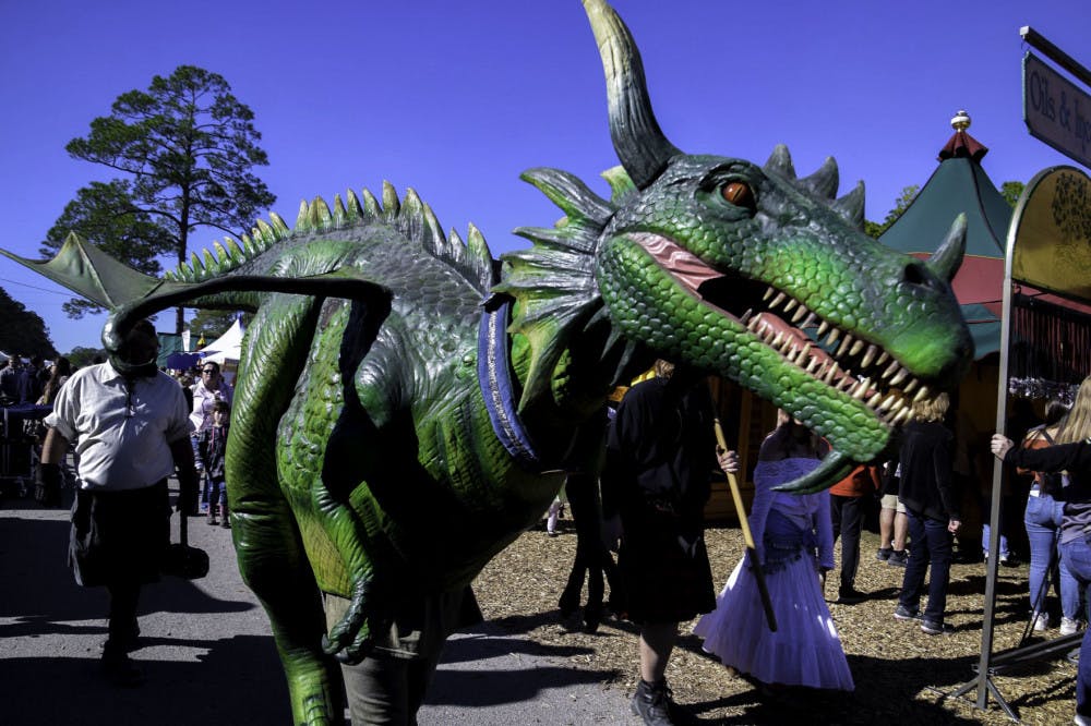 A Hoggetowne Medieval Faire participant dressed as a dragon wanders through the merchant tents.
