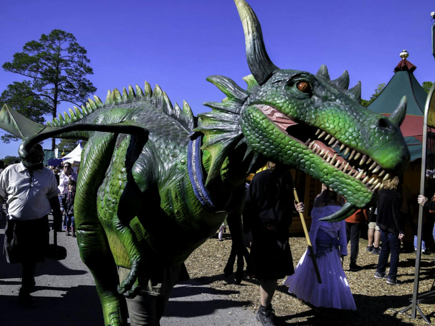 A Hoggetowne Medieval Faire participant dressed as a dragon wanders through the merchant tents.